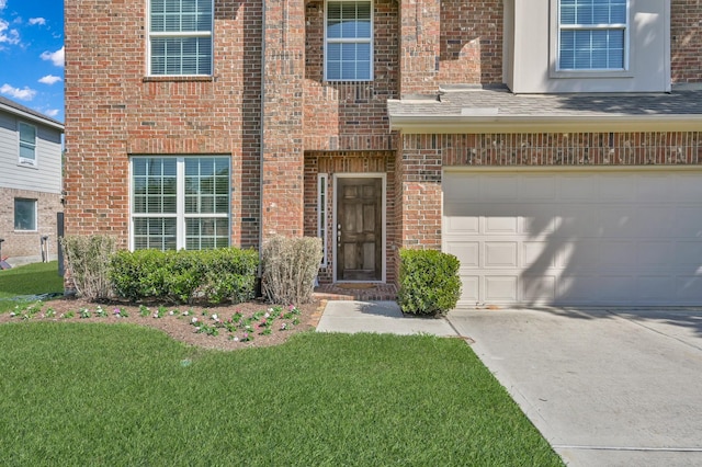 property entrance with driveway, brick siding, a yard, and a garage