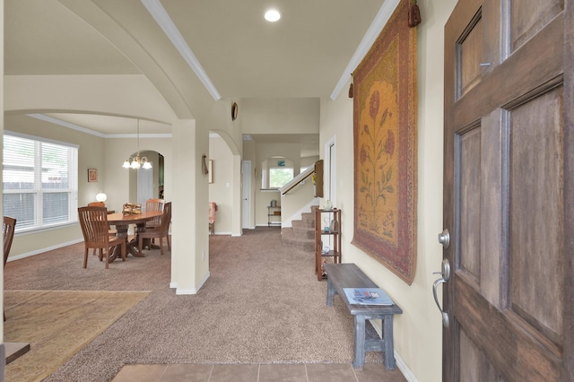entryway with light colored carpet, a chandelier, baseboards, arched walkways, and stairs