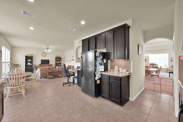 kitchen with freestanding refrigerator, arched walkways, ceiling fan, light tile patterned floors, and recessed lighting