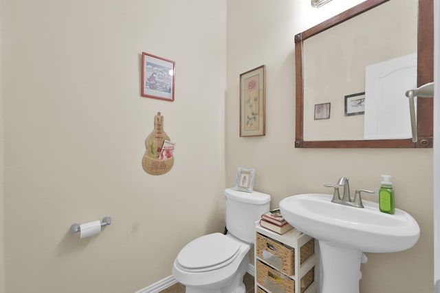 bathroom featuring toilet, baseboards, and a sink