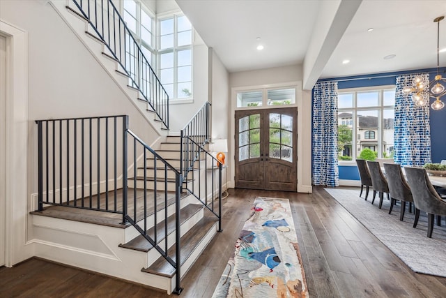foyer entrance featuring wood finished floors, a chandelier, stairs, french doors, and baseboards