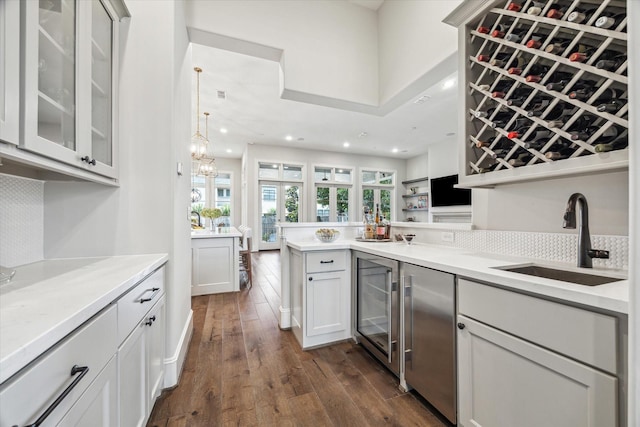 indoor wet bar with wine cooler, dark wood-style floors, decorative backsplash, recessed lighting, and a chandelier