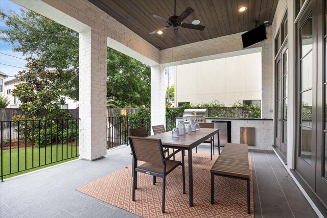 view of patio with exterior kitchen, ceiling fan, fence, a grill, and outdoor dining area