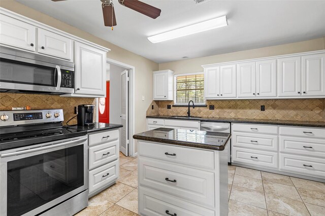 249 Hickory St, Huntsville, TX 77320 - kitchen featuring stainless steel appliances, a sink, a ceiling fan, backsplash, and white cabinetry