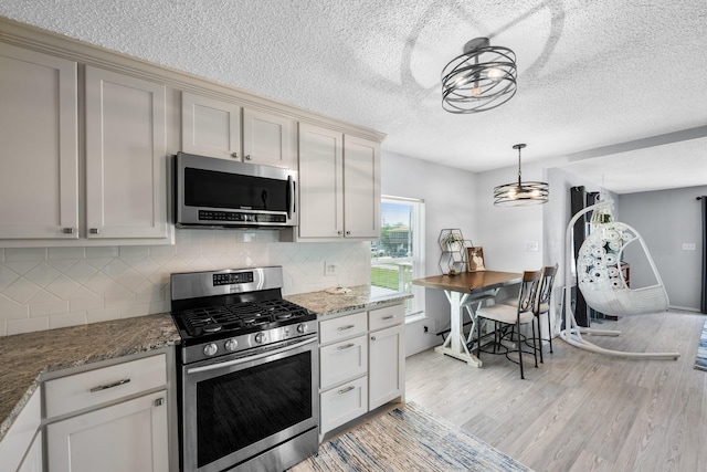 5024 County Road 476a, Freeport, TX 77541 - kitchen with appliances with stainless steel finishes, light wood finished floors, backsplash, a textured ceiling, and stone counters