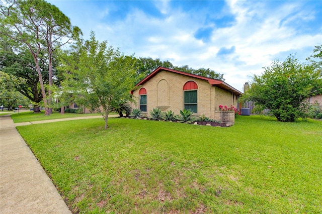 view of side of property with brick siding, a lawn, concrete driveway, and central AC