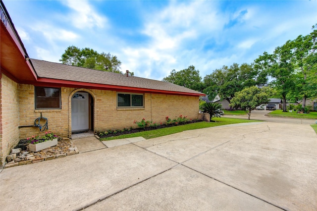 property entrance featuring brick siding and a shingled roof