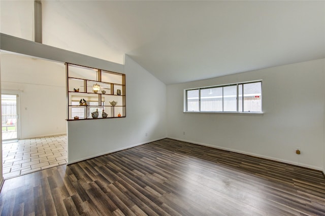 unfurnished room featuring lofted ceiling, wood finished floors, and baseboards