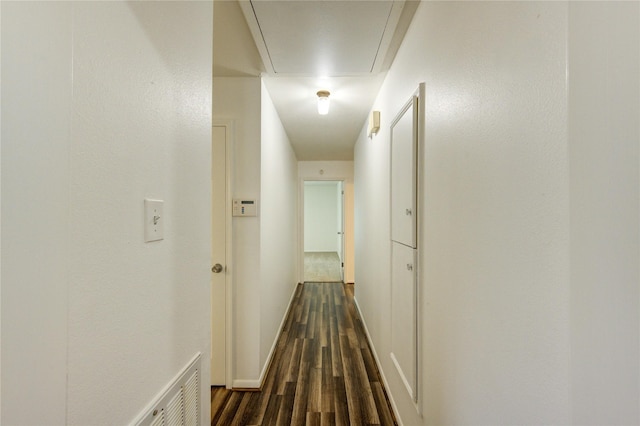 hall featuring attic access, dark wood-style flooring, and baseboards