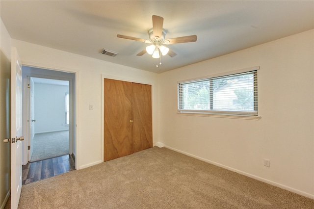 unfurnished bedroom with carpet flooring, a closet, baseboards, and a ceiling fan