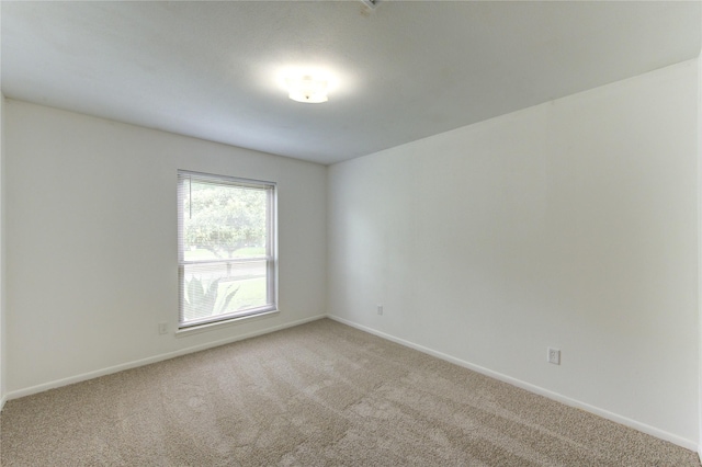 empty room featuring carpet and baseboards
