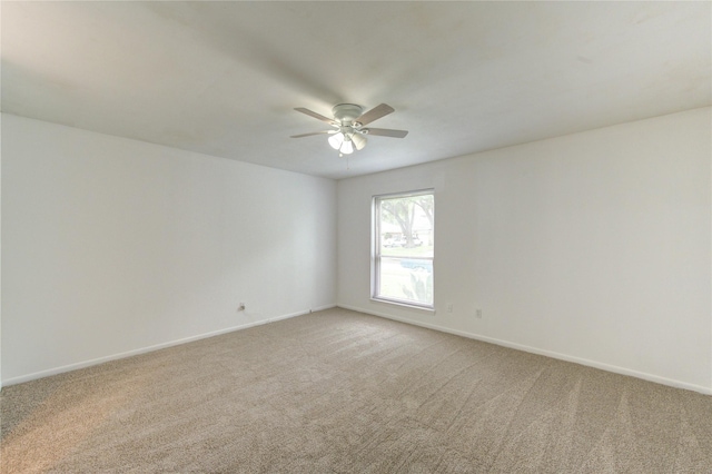 spare room featuring ceiling fan, light colored carpet, and baseboards