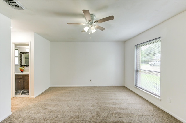 unfurnished room with light colored carpet, a ceiling fan, and baseboards