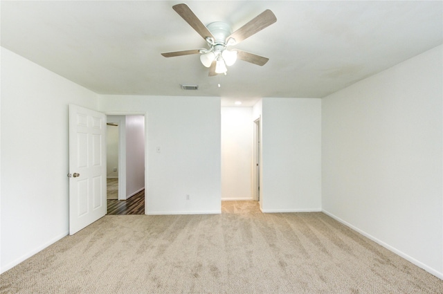 carpeted empty room featuring a ceiling fan and baseboards