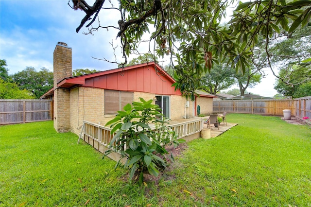 rear view of house featuring brick siding, a chimney, a deck, and board and batten siding