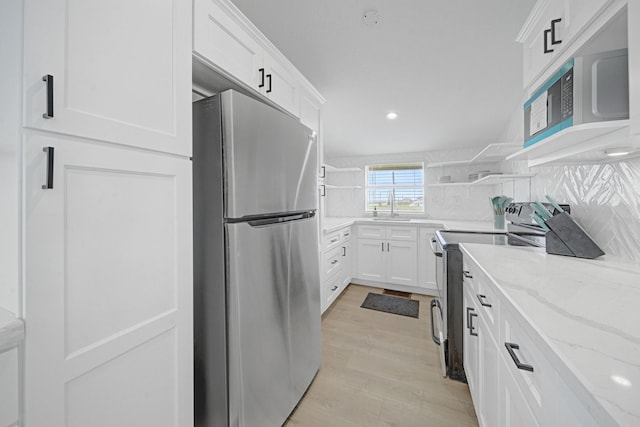 119 Nesmith Pl, Surfside Beach, TX 77541 - kitchen featuring stainless steel appliances, white cabinets, open shelves, light stone countertops, and a sink