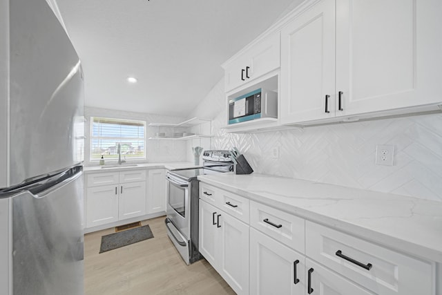 119 Nesmith Pl, Surfside Beach, TX 77541 - kitchen with stainless steel appliances, white cabinetry, light wood-style floors, and backsplash