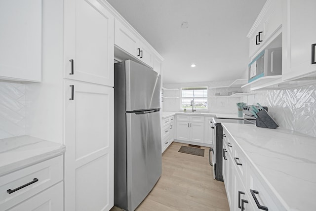 119 Nesmith Pl, Surfside Beach, TX 77541 - kitchen with appliances with stainless steel finishes, backsplash, white cabinetry, light stone countertops, and light wood-type flooring