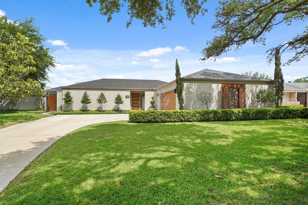 view of front of property with brick siding, a front lawn, and concrete driveway