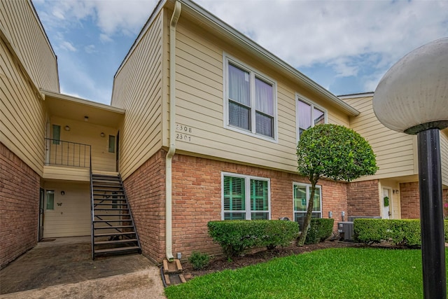 14555 Wunderlich Dr Unit 2307, Houston, TX 77069 - view of side of home with brick siding, stairs, a yard, and central AC