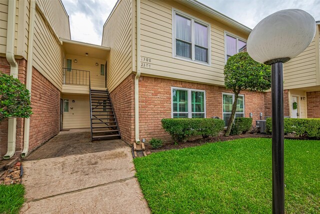 14555 Wunderlich Dr Unit 2307, Houston, TX 77069 - view of front of house with brick siding, a front lawn, stairs, and central air condition unit