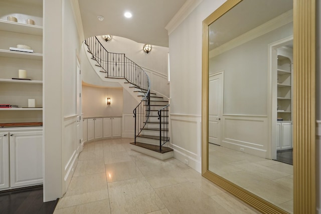 4606 W Alabama St, Houston, TX 77027 - stairway with crown molding, a decorative wall, a wainscoted wall, built in shelves, and tile patterned floors