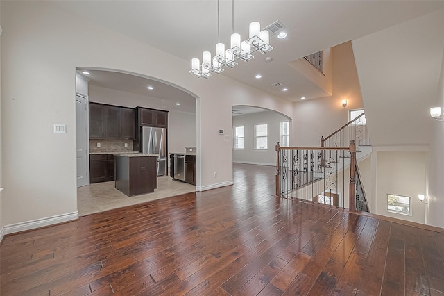 1606 Parker St, Houston, TX 77007 - unfurnished living room featuring arched walkways, light wood-type flooring, baseboards, stairs, and recessed lighting