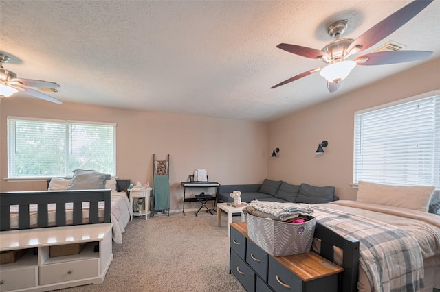 bedroom featuring light carpet, a textured ceiling, and ceiling fan