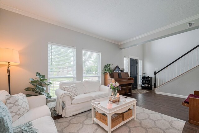 living area with ornamental molding, wood finished floors, stairway, and baseboards
