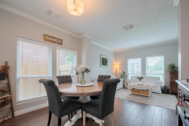 dining space featuring wood finished floors, crown molding, baseboards, and a textured ceiling