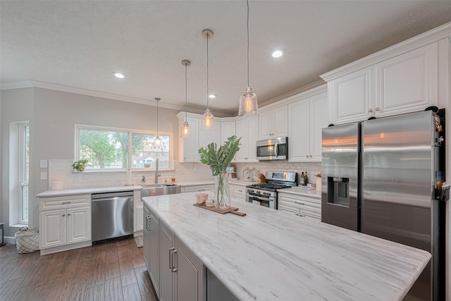 kitchen featuring stainless steel appliances, a sink, ornamental molding, white cabinetry, and decorative backsplash