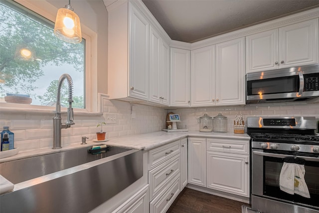 kitchen with stainless steel appliances, a sink, white cabinetry, and tasteful backsplash