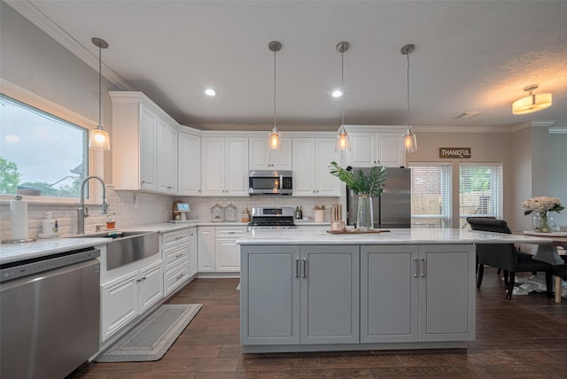 kitchen with appliances with stainless steel finishes, a center island, white cabinets, light countertops, and backsplash