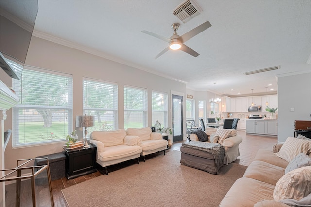 living area featuring crown molding, light wood-style flooring, ceiling fan, a chandelier, and recessed lighting