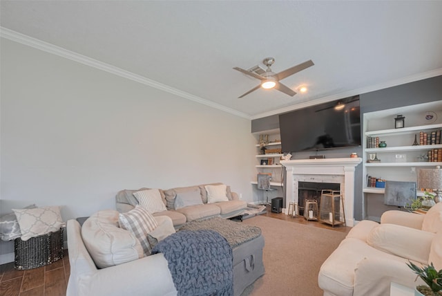 living area featuring ornamental molding, wood finished floors, a fireplace, a ceiling fan, and baseboards