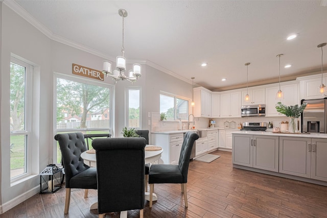 dining room with crown molding, plenty of natural light, a chandelier, wood-type flooring, and recessed lighting