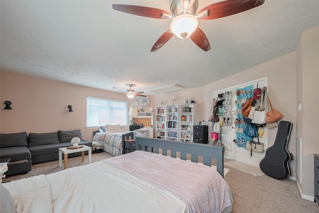 carpeted bedroom featuring attic access, a textured ceiling, ceiling fan, and baseboards