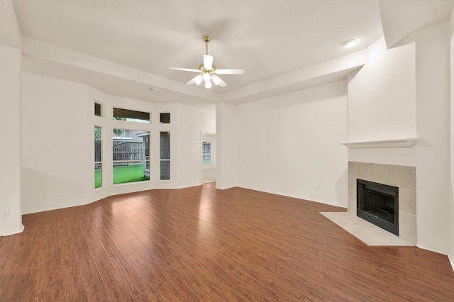 3722 Lovers Ln, Montgomery, TX 77356 - unfurnished living room with wood finished floors, a tiled fireplace, ceiling fan, and a raised ceiling