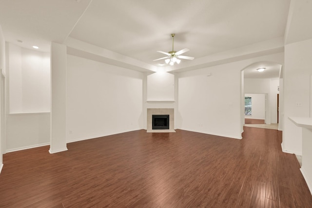 3722 Lovers Ln, Montgomery, TX 77356 - unfurnished living room with a ceiling fan, a fireplace, dark wood-style flooring, arched walkways, and baseboards