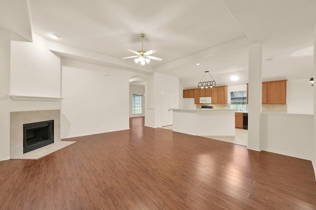 3722 Lovers Ln, Montgomery, TX 77356 - unfurnished living room with light wood-style floors, a ceiling fan, a tiled fireplace, and arched walkways