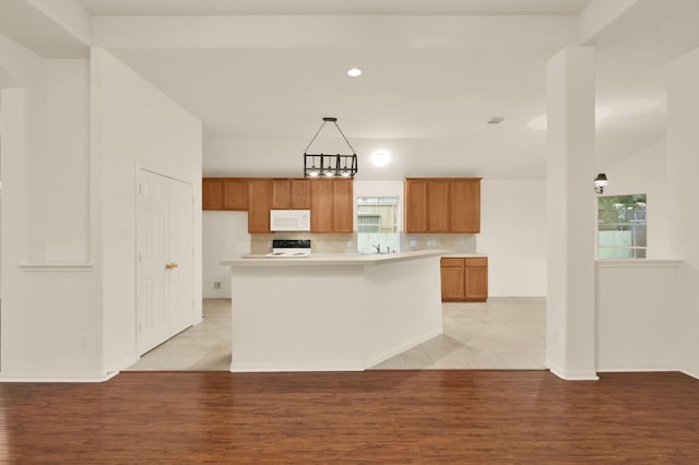 3722 Lovers Ln, Montgomery, TX 77356 - kitchen featuring white microwave, range, brown cabinetry, light wood-style flooring, and light countertops
