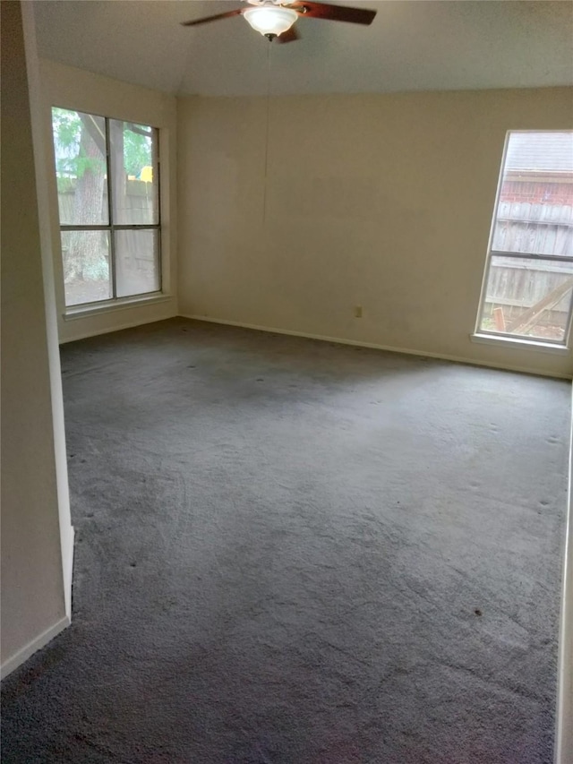 carpeted spare room with plenty of natural light, a ceiling fan, vaulted ceiling, and baseboards