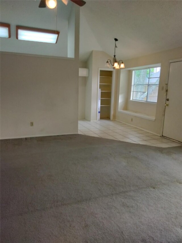 unfurnished living room featuring vaulted ceiling, carpet flooring, a chandelier, tile patterned floors, and ceiling fan