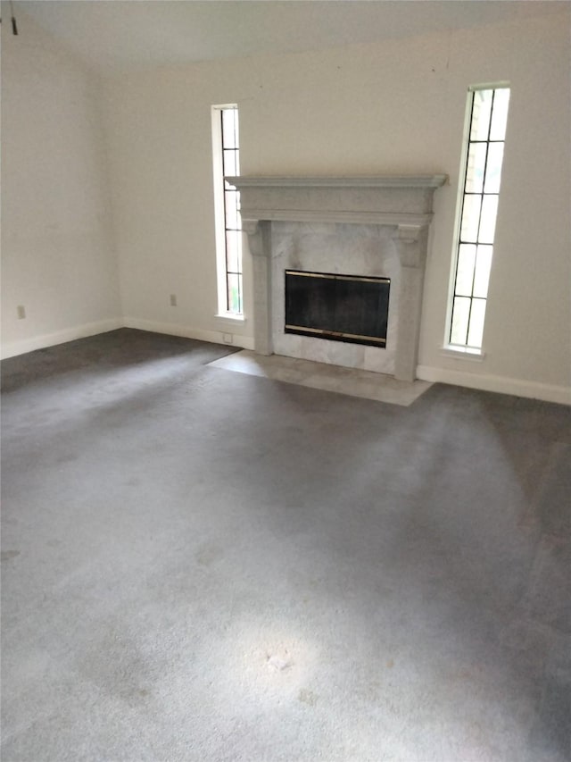 unfurnished living room with a fireplace, baseboards, and carpet flooring