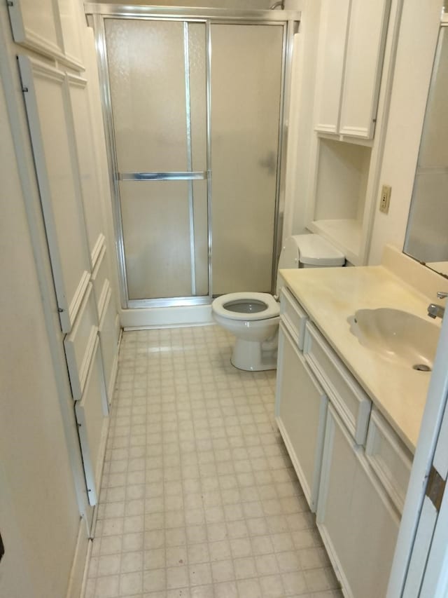 bathroom with a shower stall, toilet, vanity, and tile patterned floors