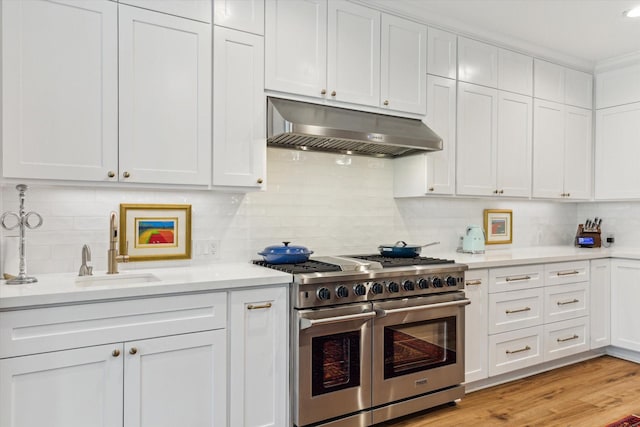 15411 Parkwood Way, Houston, TX 77059 - kitchen with range with two ovens, under cabinet range hood, a sink, light countertops, and white cabinetry