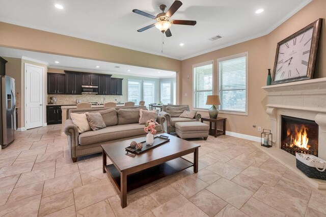 510 Pearl View Ln, Pinehurst, TX 77362 - living area with ornamental molding, a ceiling fan, baseboards, stone tile floors, and a lit fireplace