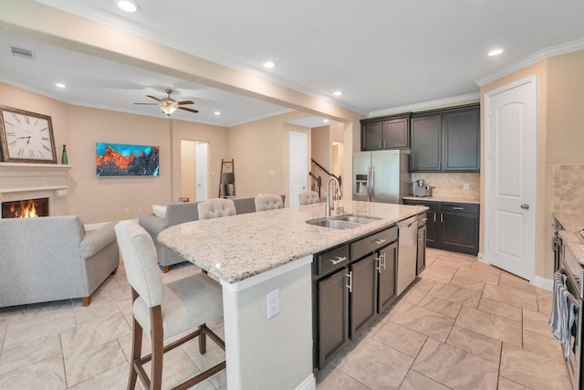 510 Pearl View Ln, Pinehurst, TX 77362 - kitchen featuring appliances with stainless steel finishes, a sink, a kitchen bar, ornamental molding, and open floor plan