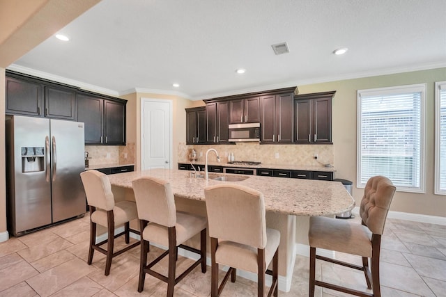 510 Pearl View Ln, Pinehurst, TX 77362 - kitchen featuring appliances with stainless steel finishes, a sink, ornamental molding, backsplash, and a kitchen island with sink