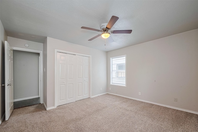 unfurnished bedroom with carpet, a closet, a textured ceiling, baseboards, and a ceiling fan